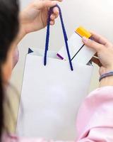 Woman putting a small box into white shopping bag photo