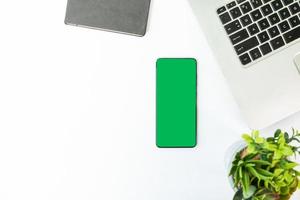 Smartphone de pantalla verde en un escritorio con portátil foto