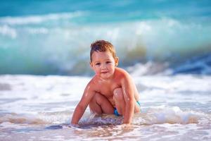 niño feliz niño divirtiéndose en el agua de mar foto
