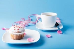 Colorful muffin on saucer with flower petal and ribbon photo