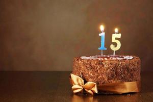 Pastel de chocolate de cumpleaños con velas encendidas como número quince. foto