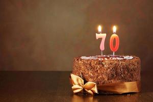 Pastel de chocolate de cumpleaños con velas encendidas como un número setenta foto