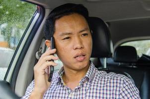 Hombre asiático hablando por teléfono en el coche foto