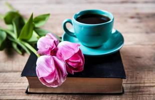 Cup of coffee on book with flowers. photo