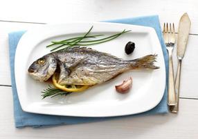 Garnished grilled whole sea bream with olives photo