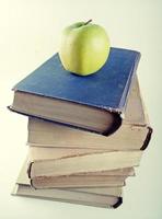 stack of old hardcover books with green apple