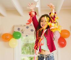 Excited girl playing with streamers at birthday party, arms up