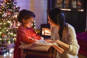 christmastime, mother and her daughter opening a gift  near tree photo