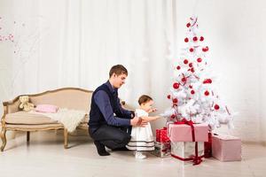niña juega con su papá cerca del árbol de navidad