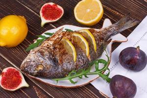 Whole grilled fish dorado served with lemon and figs; photo