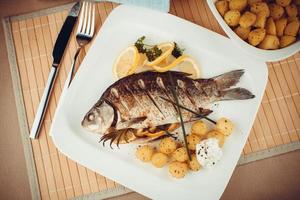 Grilled fish with rosemary potatoes and lemon photo