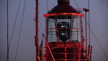 Rotating lighthouse at dusk in a harbor video