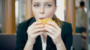 vrouw hamburger eten en frietjes glimlachen. mooi gemengd ras vrouwelijk model