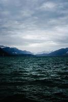 Body of water near mountain under cloudy sky photo