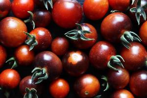 Fotografía de un montón de tomates cherry negros y rojos para el fondo de alimentos foto