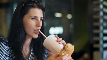 jonge vrouwen die snel voedsel eten en drinkenink melkcocktail