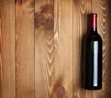 Red wine bottle on wooden table background photo