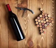Red wine bottle, corkscrew and grape shaped corks photo