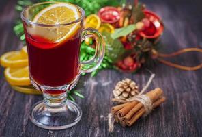 Hot wine (mulled wine) with spices on wooden background. photo