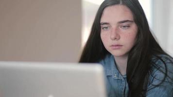 närbild porträtt av tonårsflickor som använder en bärbar dator sitter vid bordet hemma