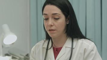 Female doctor in medical office analyzes results an electrocardiogram and takes notes video