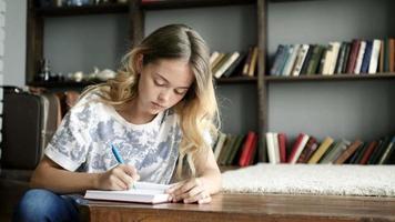 Cute teen girl writes a letter in notebook