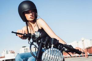 Chica motociclista sentada en una motocicleta personalizada vintage foto