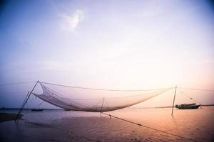 Calm scene of fishing net against purple sunset.