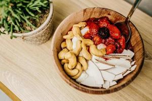 Sliced strawberries in brown wooden bowl photo