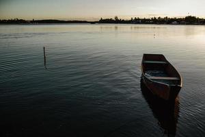 Shabby boat floating on calm lake in evening photo