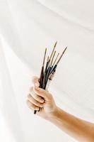 Artist's hand with brushes against cloth photo