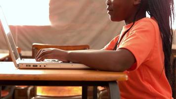 kleines Mädchen mit Laptop im Klassenzimmer
