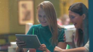 Frauen im Café lachen über etwas in Tablet-PC video