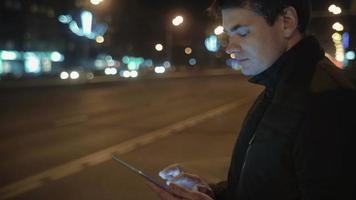 Hombre escribiendo cartas en tablet pc mientras espera el autobús video