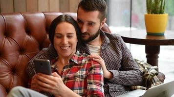 pareja joven, sentado, en, sofá, y, utilizar, gadgets video