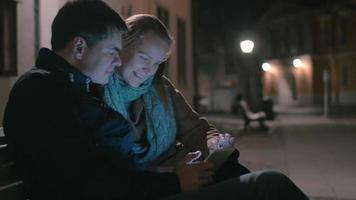 coppia seduta sulla panchina con tablet