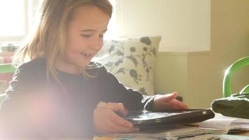 Mädchen, das am Tisch sitzt und Hausaufgaben mit digitalem Tablet macht