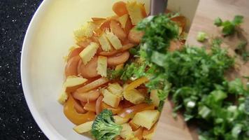 salade maken met verse kruiden, broccoli, paprika, pompoen en wortelen. geschoten op rode epische bioscoopcamera in slow motion. video