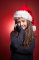 little girl in red santa hat on red background photo
