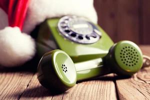 vintage phone with Santa's hat on wooden background photo