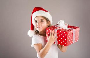 Small girl in santa hat with christmas gift photo