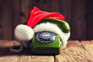 vintage phone with Santa's hat on wooden background photo