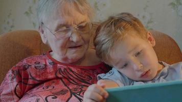 niño mostrando algo en tableta a su abuela