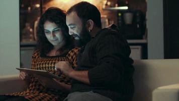 casal usando tablet no sofá à noite no quarto