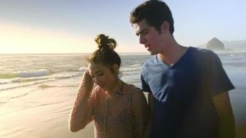 casal atraente caminhando na praia juntos video