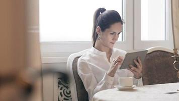 mulher usando tablet e bebendo café na mesa