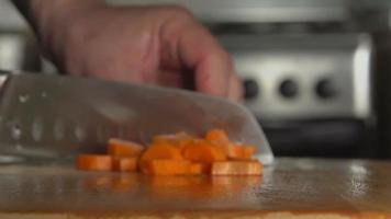 de hand van een kok snijdt een wortel met een mes