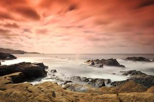 Formación de roca negra en la orilla del mar durante el día foto