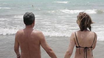 Happy senior couple walking together into the sea