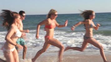Grupo de amigos adolescentes corriendo juntos por la playa